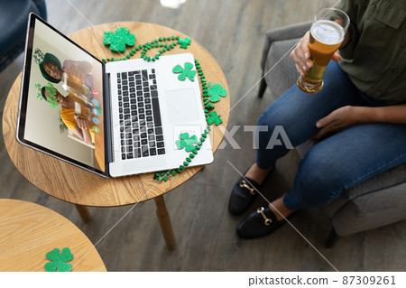Caucasian woman holding beer at bar making st patrick's day video call with friends on laptop Caucasian woman holding beer at bar making st patrick's day video call with friends on laptop 87309261