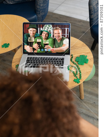 Man at bar making st patrick's day video call with three smiling caucasian male friends on laptop Man at bar making st patrick's day video call with three smiling caucasian male friends on laptop 87309381