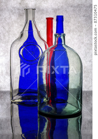 Still life with glass multicolored dishes on a gray background Still life with glass multicolored dishes on a gray background 87310475