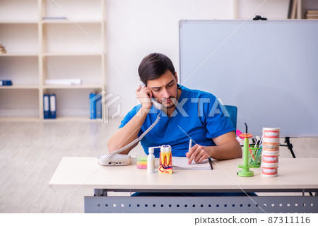 Young male dentist lecturer in front of whiteboard Young male dentist lecturer in front of whiteboard 87311116