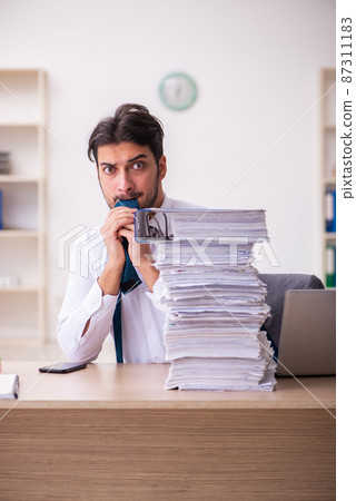 Young businessman employee unhappy with excessive work in the office Young businessman employee unhappy with excessive work in the office 87311183