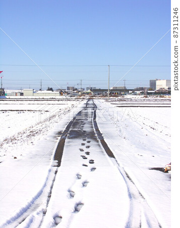 Farm road scenery with footprints and tire marks the next morning after snow in early spring Farm road scenery with footprints and tire marks the next morning after snow in early spring 87311246