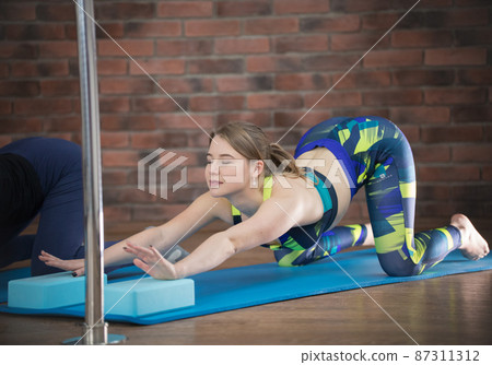 Young pretty woman in colorful blue leggings performing lower back deflection 87311312