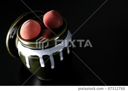 拍一張黑色背景下罐子裡的脆李子的照片 87312788