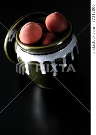 Take a picture of the crispy plums in the jar on a black background Take a picture of the crispy plums in the jar on a black background 87312800