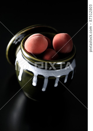 Take a picture of the crispy plums in the jar on a black background Take a picture of the crispy plums in the jar on a black background 87312803