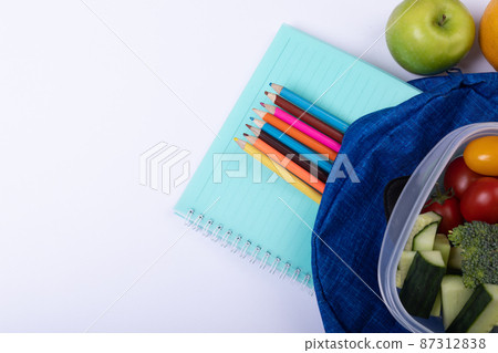 Directly above shot of healthy food and tiffin with school supplies on white background, copy space 87312838