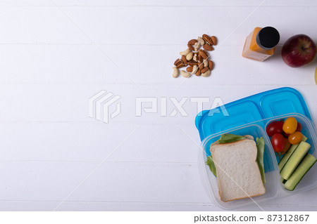 Directly above shot of healthy food and tiffin box by juice bottle over white background, copy space 87312867