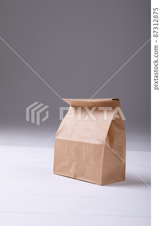 Close-up of brown paper lunch bag on table against gray background with copy space 87312875