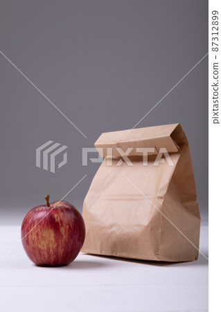 Apple and paper lunch bag on table against gray background with copy space Apple and paper lunch bag on table against gray background with copy space 87312899