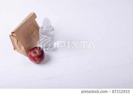 High angle view of paper lunch bag with apple and water bottle on white background along copy space 87312933