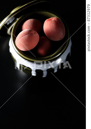 A bird's-eye view of the crispy plums in the jar on a black background 87312979