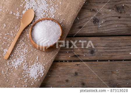 High angle view of white rock salt in wooden bowl by spoon on jute fabric at table 87313028