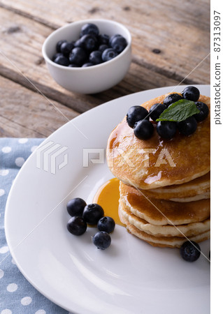 Close-up of appetizing pancakes with syrup, herb and blueberries served in plate on table Close-up of appetizing pancakes with syrup, herb and blueberries served in plate on table 87313097