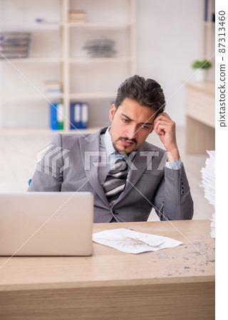Young male employee unhappy with excessive work in the office Young male employee unhappy with excessive work in the office 87313460