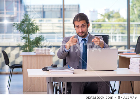 Young male employee in wheel-chair working in the office Young male employee in wheel-chair working in the office 87313479