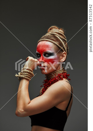 close up portrait of young beautiful girl with colorful face painting. Halloween professional makeup. neck and hands are wrapped with ropes. Victim Concept close up portrait of young beautiful girl with colorful face painting. Halloween professional makeup. neck and hands are wrapped with ropes. Victim Concept 87313542