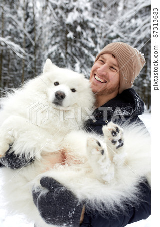 A human and a dog are best friends. Man and dog walk in snowy forest in winter in deep snow on a sunny day. A human and a dog are best friends. Man and dog walk in snowy forest in winter in deep snow on a sunny day. 87313683