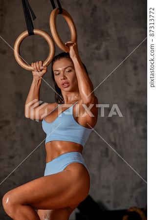 Working out Young athletic sportswoman exercising on gymnastic rings at gym Exercising woman holding gymnast rings and looking up. Workout at gym. Concept of power, strength, healthy lifestyle, sport. Working out Young athletic sportswoman exercising on gymnastic rings at gym Exercising woman holding gymnast rings and looking up. Workout at gym. Concept of power, strength, healthy lifestyle, sport. 87313772