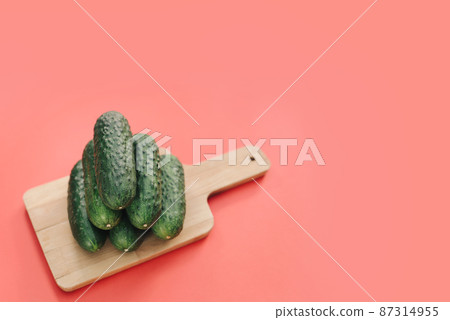 Cucumbers on a wooden board on a pink background. Cucumbers on a wooden board on a pink background. 87314955