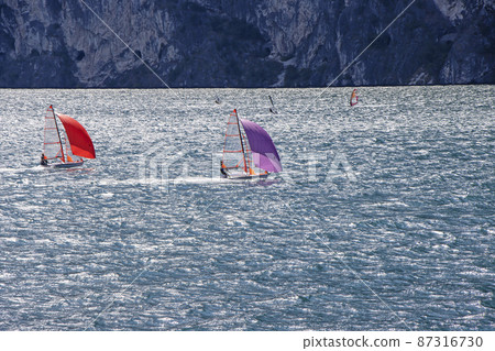 Small sailboats sail on Lake Lago di Garda in Italy 87316730