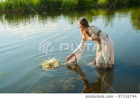 Attractive woman lowers wreath in water Attractive woman lowers wreath in water 87316744