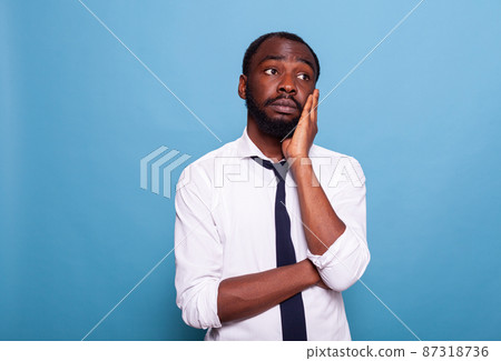 Portrait of businessman having deep thoughts holding palm of hand to his face Portrait of businessman having deep thoughts holding palm of hand to his face 87318736