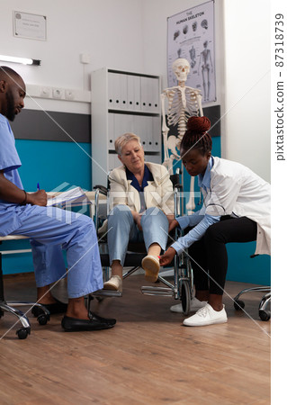 Senior woman patient geeting knee examined during physiotherapy consultation Senior woman patient geeting knee examined during physiotherapy consultation 87318739