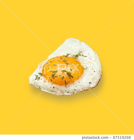 Chicken fried egg sprinkled with herbs isolated on on yellow background. Scrambled eggs close-up. Chicken fried egg sprinkled with herbs isolated on on yellow background. Scrambled eggs close-up. 87319208