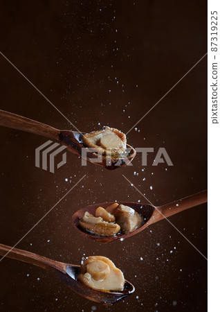 Pickled Boletus mushrooms on wooden spoons on dark background. Salt is poured on the mushrooms. The concept of delicacies. Photo with copy space. 87319225