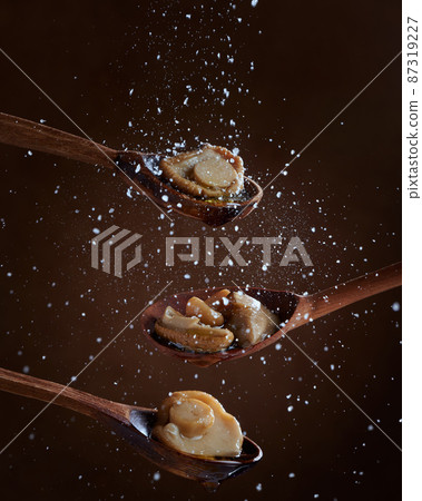 Pickled Boletus mushrooms on wooden spoons on dark background. Salt is poured on the mushrooms. The concept of homemade preparations. Pickled Boletus mushrooms on wooden spoons on dark background. Salt is poured on the mushrooms. The concept of homemade preparations. 87319227