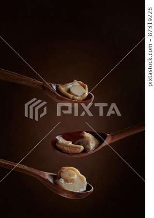 Pickled Boletus mushrooms on wooden spoons on dark background. 87319228
