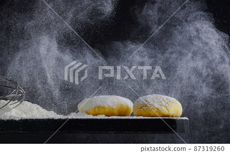 Raw dough blanks on a black background. Bakery concept. Flour pours on the table. Photo with copy space. Raw dough blanks on a black background. Bakery concept. Flour pours on the table. Photo with copy space. 87319260
