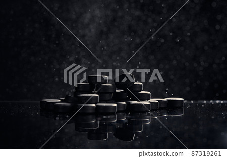 Pharmaceutical kit on a black background. Activated carbon tablets. The concept of cleansing the body of toxins. 87319261