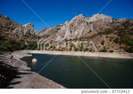 View of lake in mountains in summer with vacationing tourists 87319413