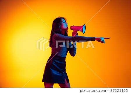 Beautiful young excited girl, student with long dark hair isolated on gradient yellow background in neon light. Concept of emotions, youth 87321135