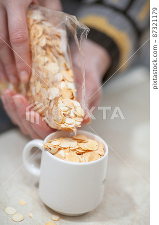 Two hands pour pea flakes into a cup Two hands pour pea flakes into a cup 87321179