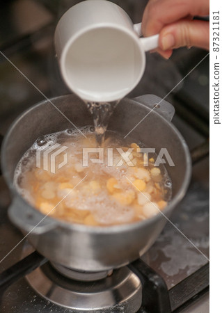 Adding water to boiling pea flakes porridge 87321181