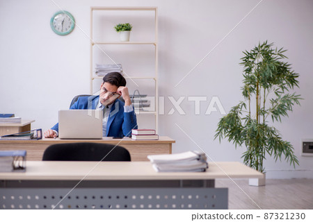 Young male employee being unhappy with excessive work 87321230