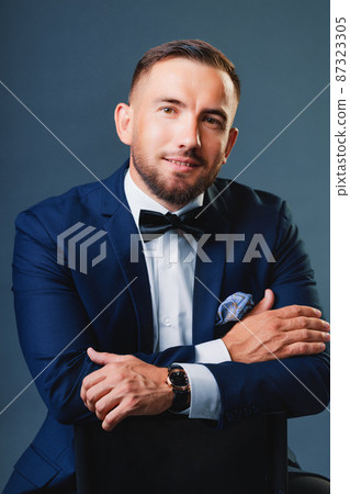 Caucasian man of 30-35 years old in business classic suit sits on chair and looks straight into Caucasian man of 30-35 years old in business classic suit sits on chair and looks straight into 87323305