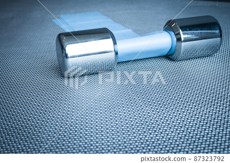 Silver dumbbell next to elastic band for pilates exercises 87323792