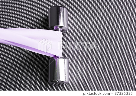 Silver dumbbell next to elastic band for pilates exercises 87325355