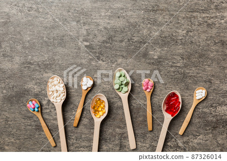 Top view Variety of vitamin and mineral pills in wooden spoon on Colored background. Top view of assorted pharmaceutical medicine pills. Dietary supplement healthcare product Top view Variety of vitamin and mineral pills in wooden spoon on Colored background. Top view of assorted pharmaceutical medicine pills. Dietary supplement healthcare product 87326014
