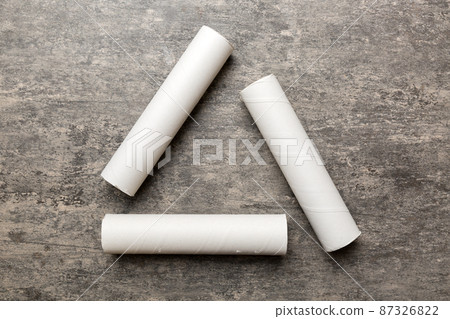 Empty toilet paper roll on colored background. Recyclable paper tube with metal plug end made of kraft paper or cardboard in the form of a recycling sign Empty toilet paper roll on colored background. Recyclable paper tube with metal plug end made of kraft paper or cardboard in the form of a recycling sign 87326822