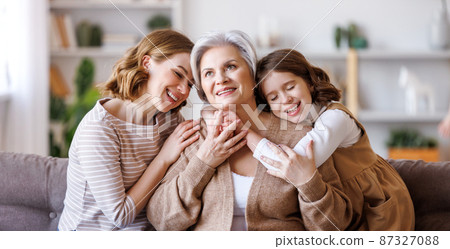 Happy multi generational family: senior woman with daughter and granddaughter on couch Happy multi generational family: senior woman with daughter and granddaughter on couch 87327088