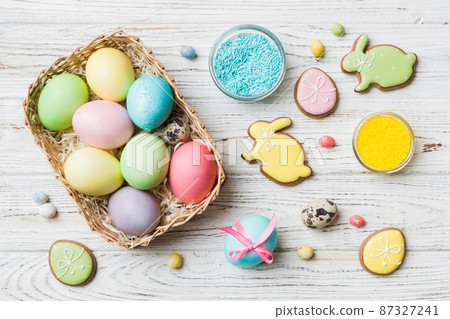 Colorful easter cookies in basket with Multi colors Easter eggs on colored background . Pastel color Easter eggs. holiday concept with copy space Colorful easter cookies in basket with Multi colors Easter eggs on colored background . Pastel color Easter eggs. holiday concept with copy space 87327241