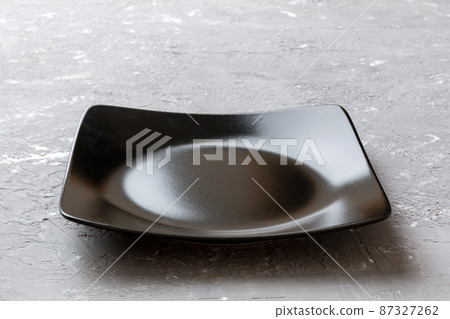 Perspective view of empty square plate on cement background. Empty space for your design Perspective view of empty square plate on cement background. Empty space for your design 87327262