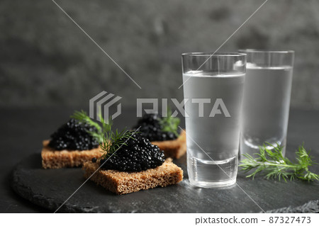 Cold Russian vodka and sandwiches with black caviar on table, closeup Cold Russian vodka and sandwiches with black caviar on table, closeup 87327473