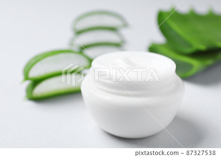 Open jar of cream and cut aloe on light background, closeup Open jar of cream and cut aloe on light background, closeup 87327538