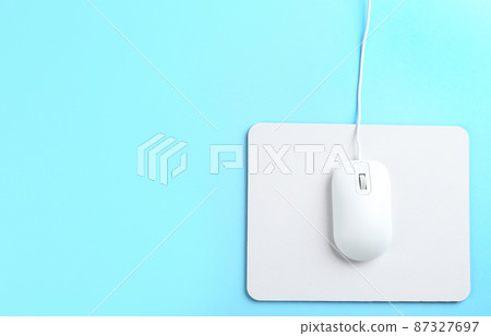 Modern wired mouse and white pad on light blue background, top view. Space for text 87327697